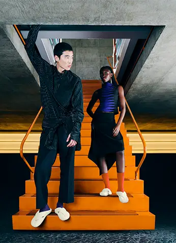 Models wearing Havaianas Top Toe Mule on a red staircase