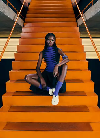 Model wearing Havaianas Top Toe Mule while sitting on a red staircase